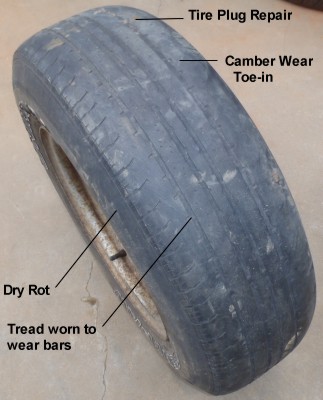 USED TIRE SHOWING DRY ROT, CAMBER WEAR, A TIRE PLUG, AND WEAR BELOW THE WEAR BARS